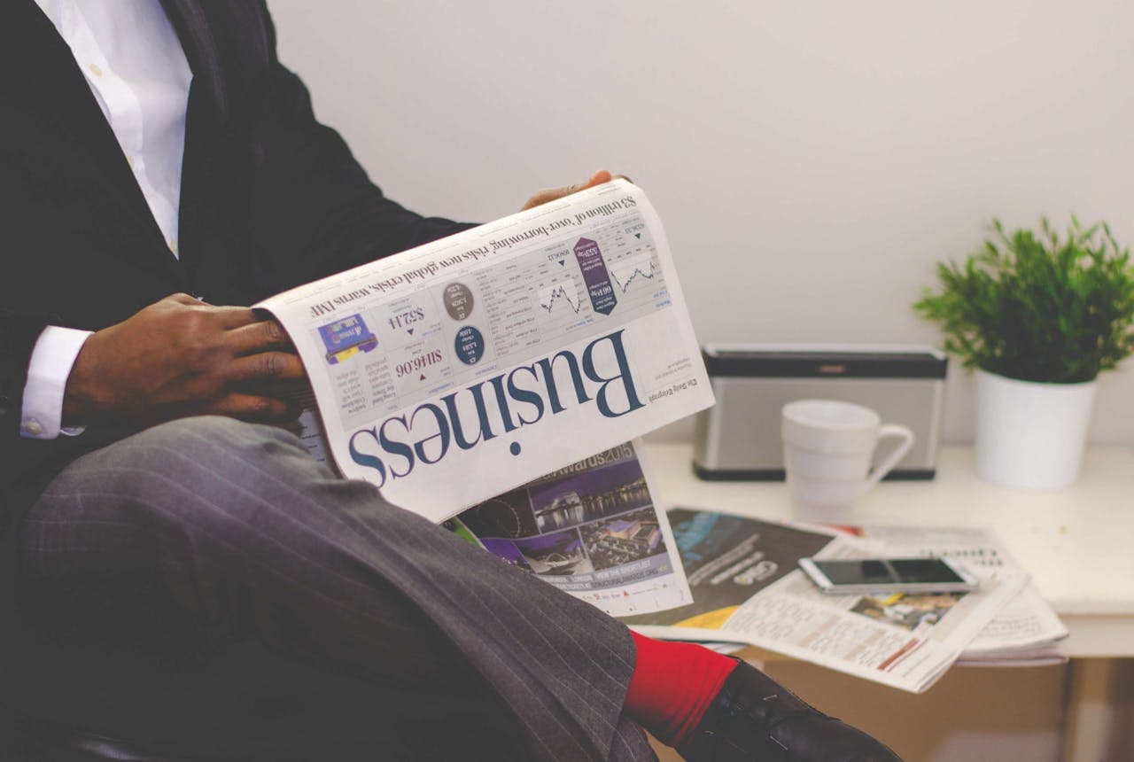 about-us Businessman reading a financial newspaper at a desk, highlighting finance and commerce theme.