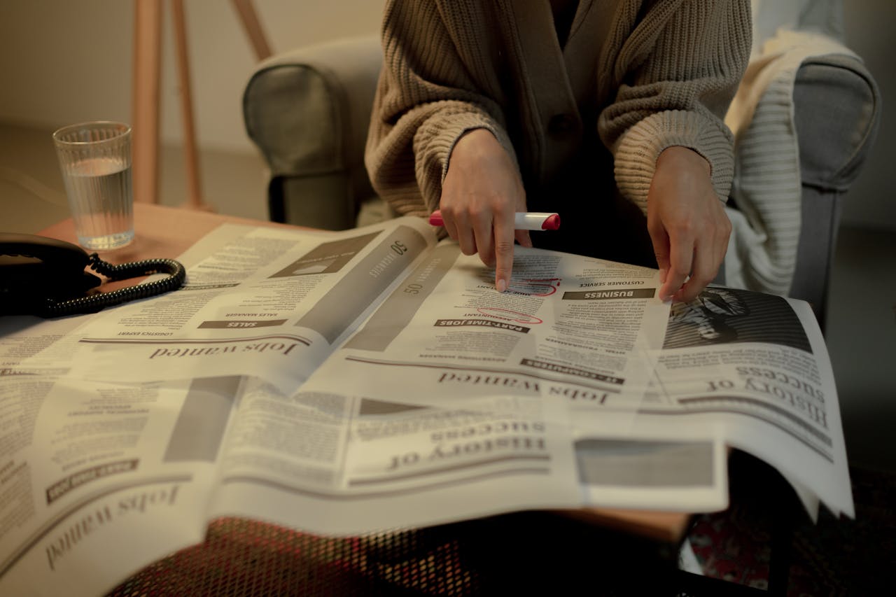 our-story Close-up of a woman reading job listings in a newspaper, highlighting employment search.